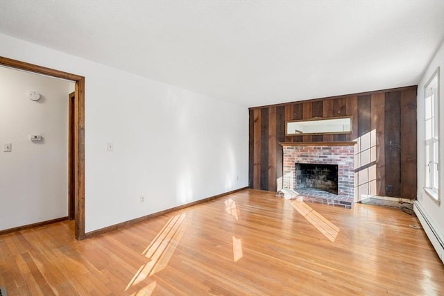 209 Pleasant, Millis, MA 02054 - unfurnished living room featuring a baseboard radiator, light wood finished floors, a fireplace, wood walls, and baseboards