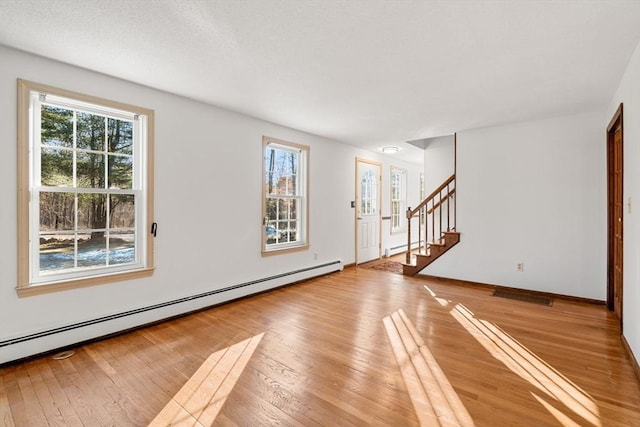 209 Pleasant, Millis, MA 02054 - unfurnished living room with baseboard heating, plenty of natural light, and light wood-style flooring