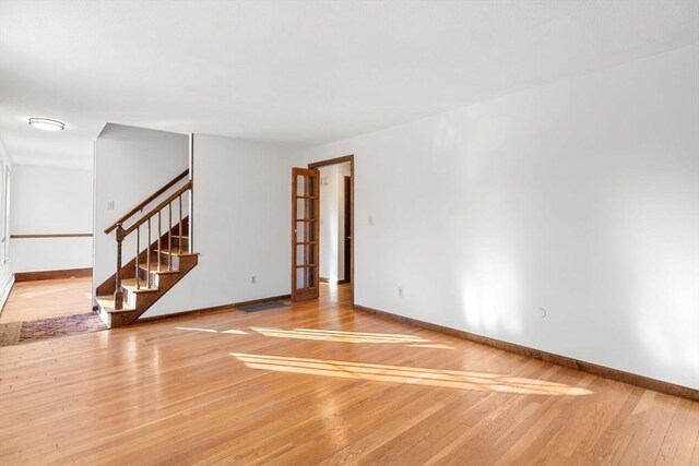 209 Pleasant, Millis, MA 02054 - unfurnished living room with light wood-style floors, stairway, and baseboards