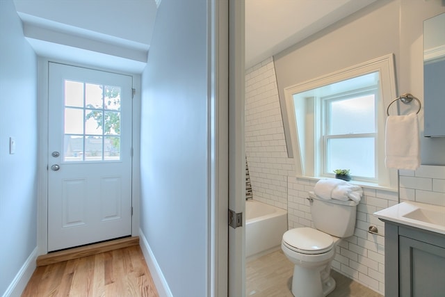 full bathroom featuring toilet, vanity, tile walls,  shower combination, and hardwood / wood-style flooring