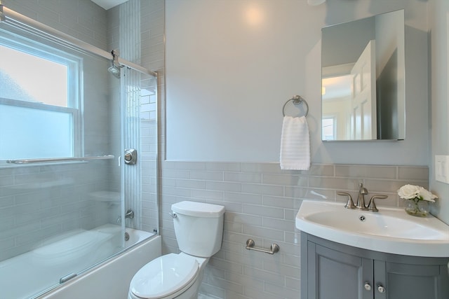 full bathroom with vanity, tile walls, combined bath / shower with glass door, decorative backsplash, and toilet