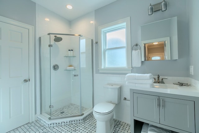 bathroom with vanity, tile walls, a shower with shower door, toilet, and tile patterned flooring