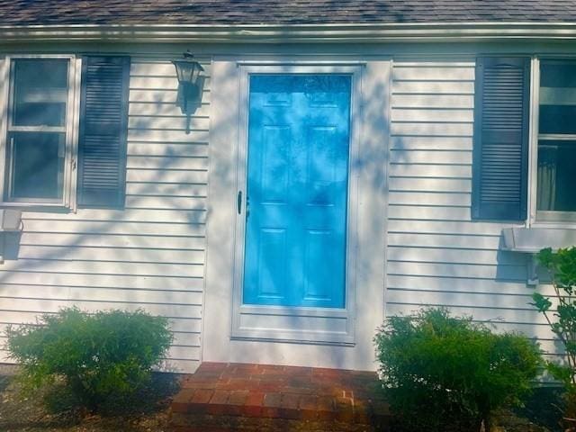 doorway to property featuring roof with shingles