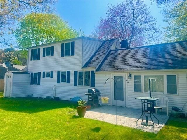 back of house featuring a yard, a shingled roof, a chimney, and a patio area