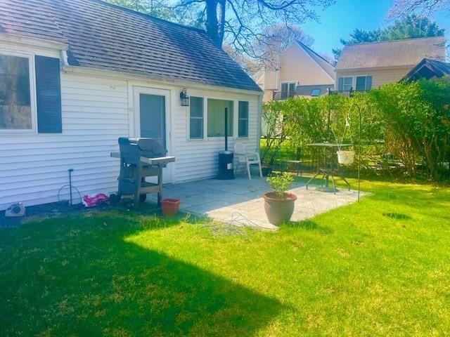 back of house featuring a patio, a shingled roof, and a lawn