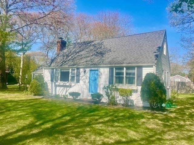 view of front of home with a chimney, a front lawn, and roof with shingles