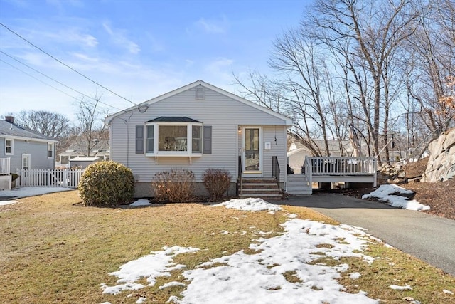 bungalow-style home with a wooden deck, a lawn, driveway, and fence