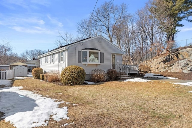 view of side of home featuring fence, an outbuilding, a lawn, and a shed