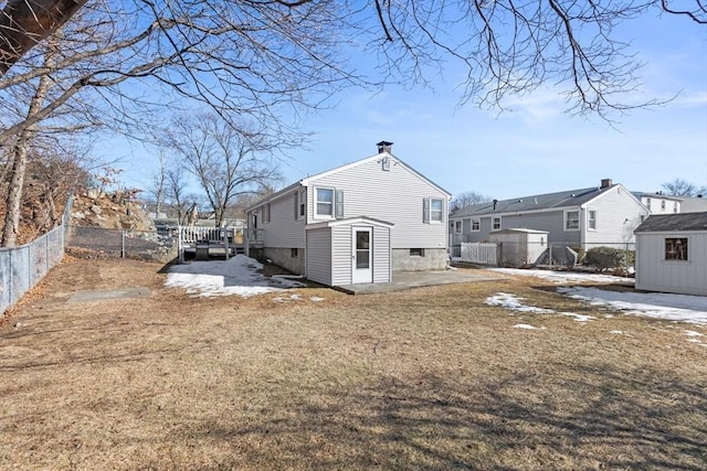 rear view of house with an outbuilding, a shed, fence, a residential view, and a chimney