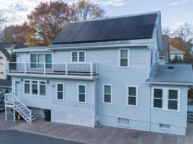 rear view of property featuring solar panels and a balcony