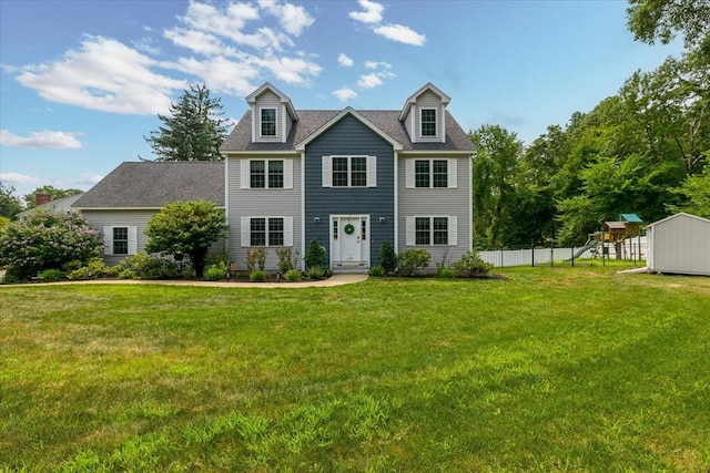 colonial inspired home featuring a front lawn, a playground, fence, and a storage shed