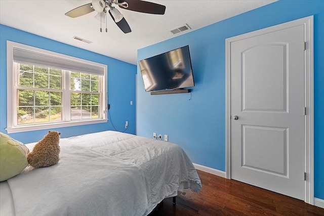 bedroom featuring ceiling fan, baseboards, visible vents, and wood finished floors