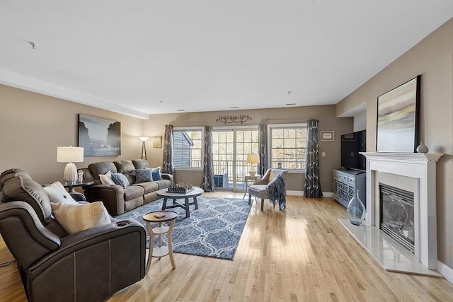 living room featuring a fireplace, baseboards, and light wood finished floors