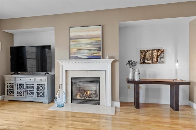 living area featuring a glass covered fireplace, baseboards, and wood finished floors