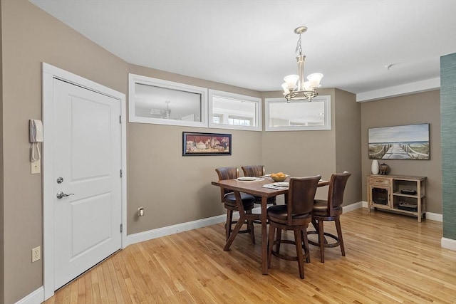 dining area featuring a chandelier, baseboards, and light wood-style flooring