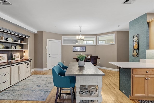 dining room featuring a notable chandelier, visible vents, light wood-style flooring, and baseboards