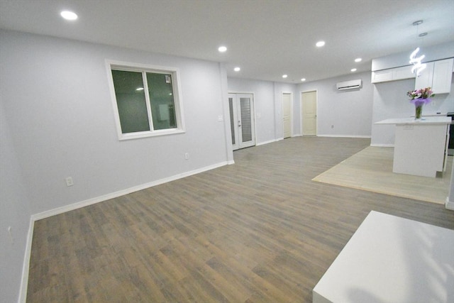 unfurnished living room featuring baseboards, a wall mounted air conditioner, wood finished floors, and recessed lighting