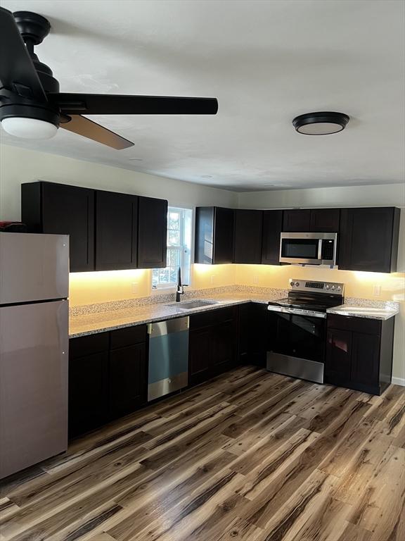 kitchen featuring light stone countertops, sink, hardwood / wood-style floors, and appliances with stainless steel finishes