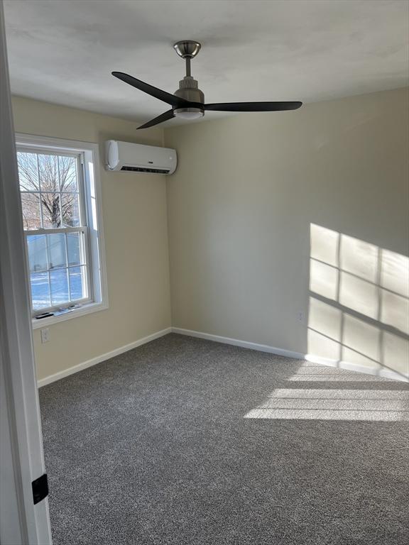 carpeted empty room featuring ceiling fan and a wall mounted air conditioner