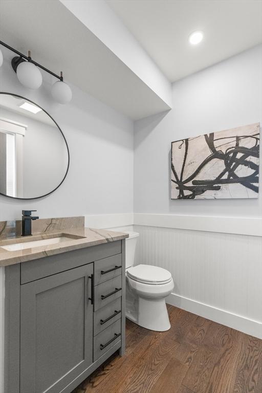 bathroom featuring vanity, toilet, wood finished floors, and a wainscoted wall