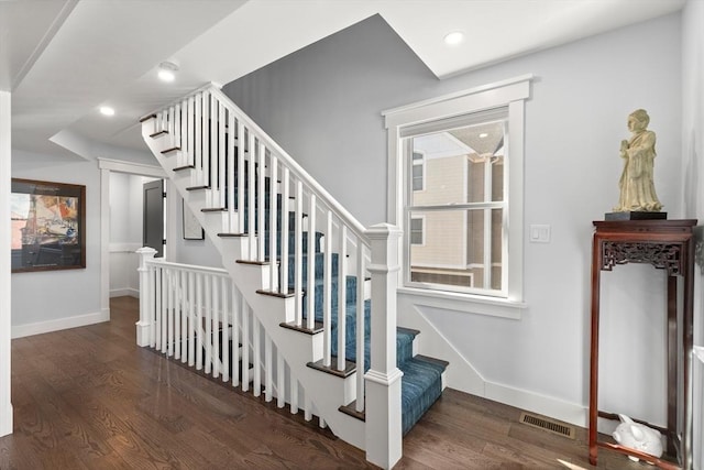 stairway featuring visible vents, baseboards, and wood finished floors