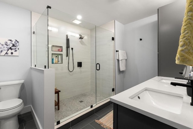 bathroom featuring tile patterned flooring, a stall shower, toilet, and a sink