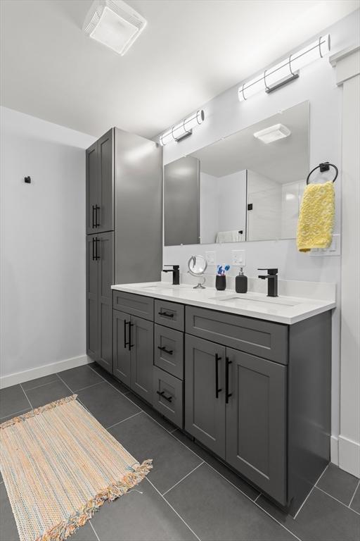 full bath with a sink, baseboards, double vanity, and tile patterned floors