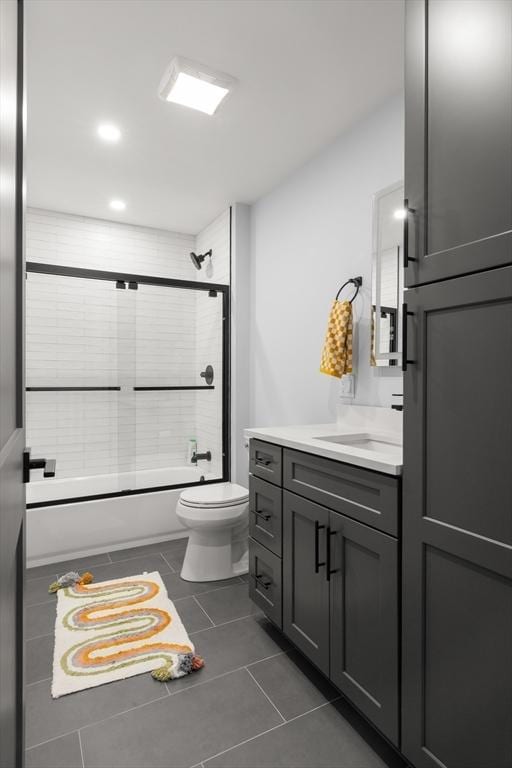 bathroom featuring vanity, tile patterned floors, toilet, and enclosed tub / shower combo