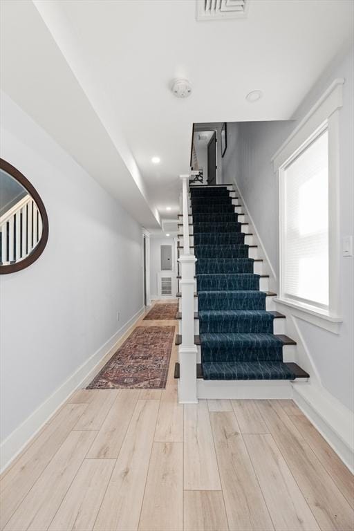 stairway with recessed lighting, visible vents, baseboards, and wood finished floors