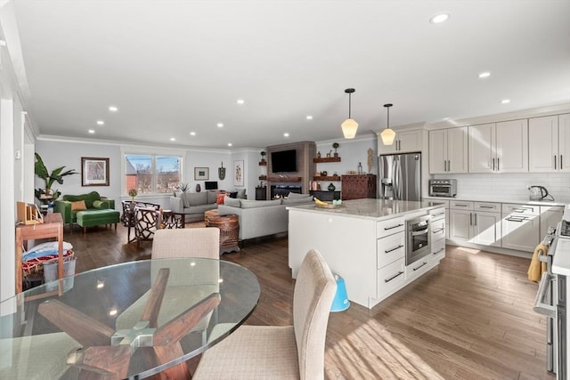 dining space featuring a toaster, wood finished floors, recessed lighting, and ornamental molding