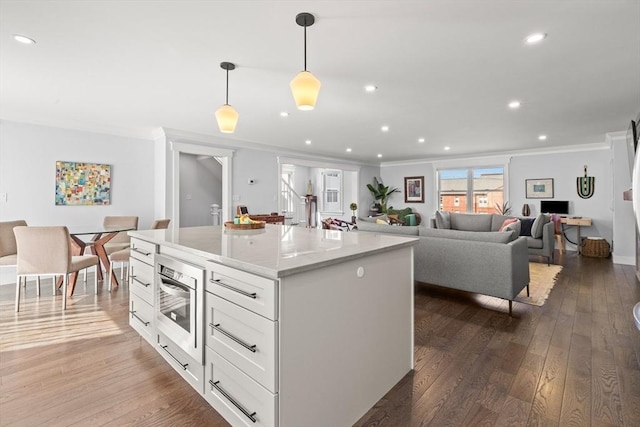 kitchen featuring white cabinetry, crown molding, dark wood finished floors, and a center island