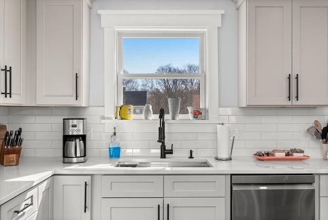 kitchen featuring a sink, backsplash, dishwasher, and light countertops