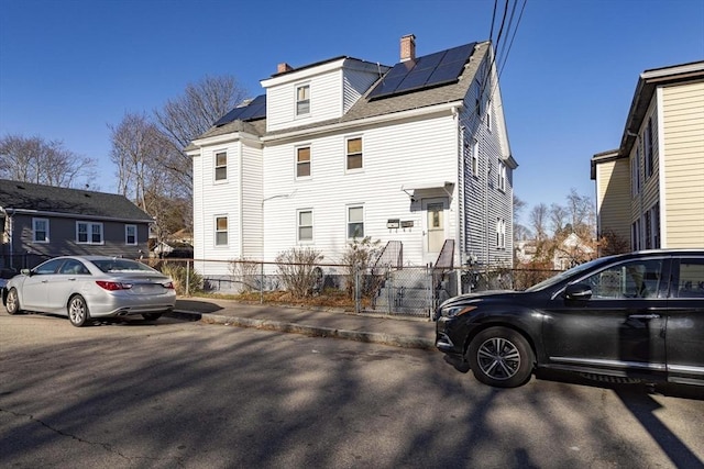 43 Huntington St, Brockton, MA 02301 - view of side of property featuring roof mounted solar panels, a chimney, and roof with shingles