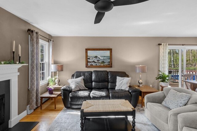 living room featuring a ceiling fan, a wealth of natural light, light wood-style flooring, and a fireplace