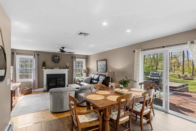 dining room featuring a ceiling fan, visible vents, a baseboard heating unit, light wood finished floors, and recessed lighting