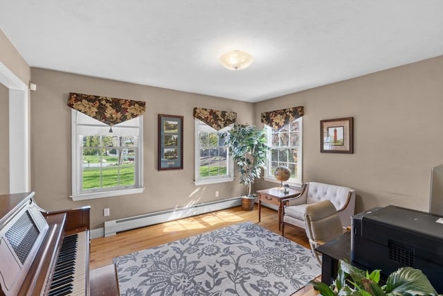 sitting room with baseboards, a baseboard radiator, and wood finished floors