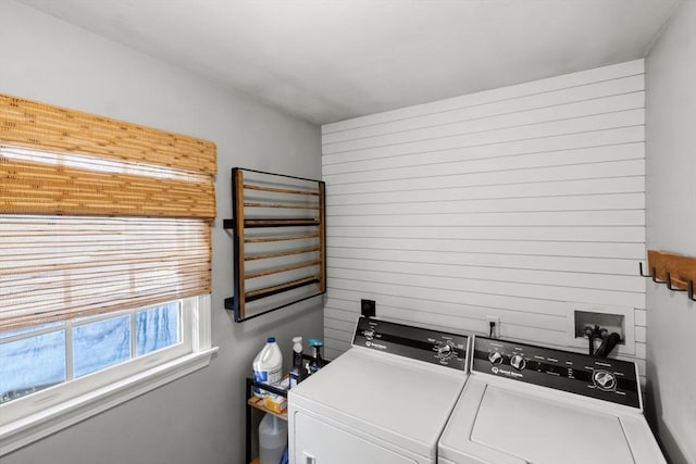 clothes washing area with laundry area, independent washer and dryer, and wooden walls