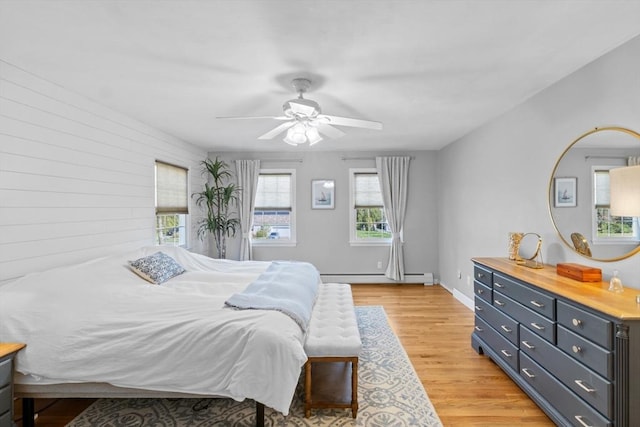 bedroom with a ceiling fan, a baseboard heating unit, and light wood-style flooring