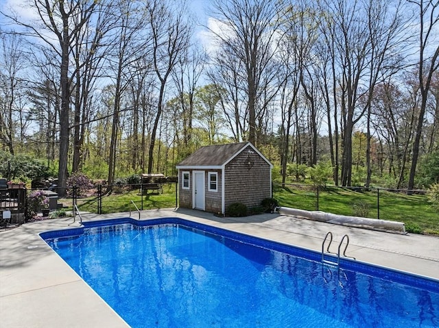 view of pool featuring fence, an outdoor structure, a covered pool, and a storage shed