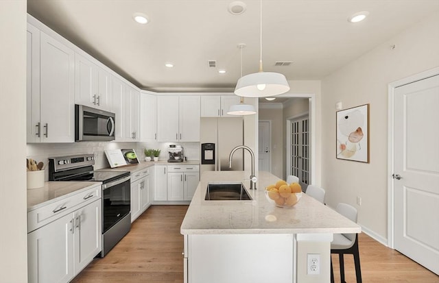 2 Codman Way Unit 305, Westborough, MA 01581 - kitchen featuring appliances with stainless steel finishes, a sink, a breakfast bar area, backsplash, and white cabinets