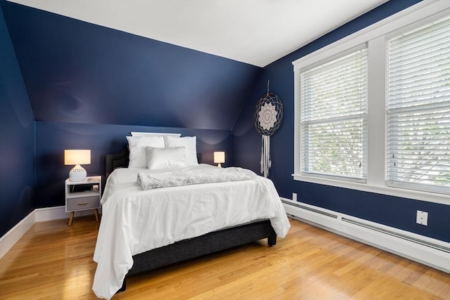 247 Ash St Unit 3, Waltham, MA 02453 - bedroom featuring a baseboard heating unit, vaulted ceiling, wood finished floors, and baseboards