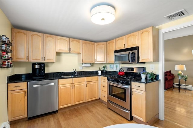 247 Ash St Unit 3, Waltham, MA 02453 - kitchen with stainless steel appliances, light brown cabinetry, a sink, baseboard heating, and light wood-style floors