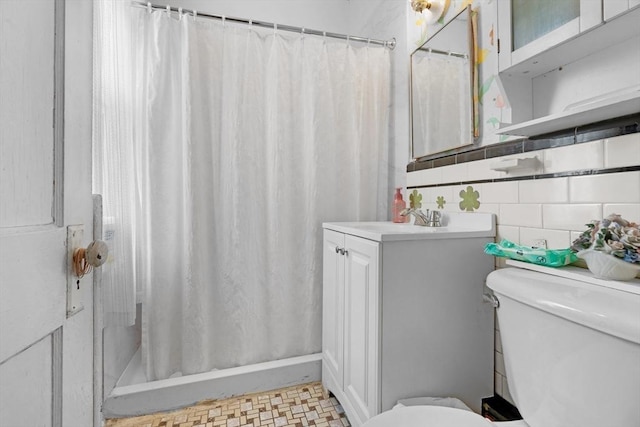 bathroom featuring toilet, curtained shower, tile walls, and vanity