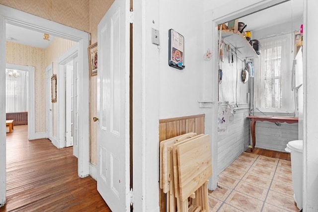 hall with light wood-style floors, baseboards, and wallpapered walls