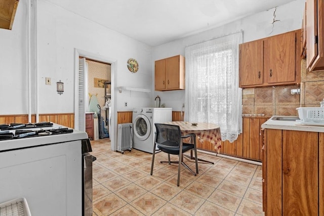 kitchen featuring light tile patterned floors, radiator heating unit, white gas range oven, and brown cabinets