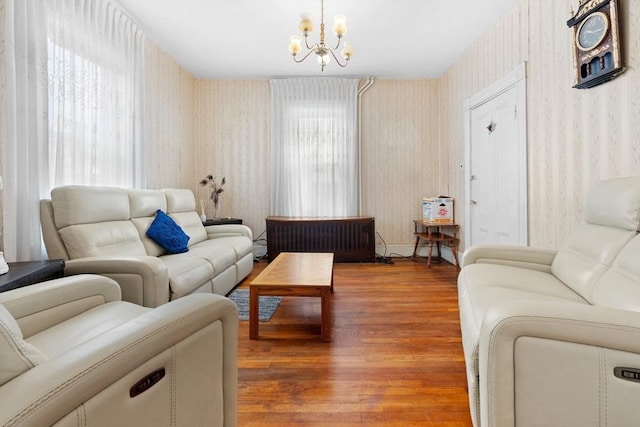 living area featuring a wealth of natural light, wood finished floors, an inviting chandelier, and wallpapered walls