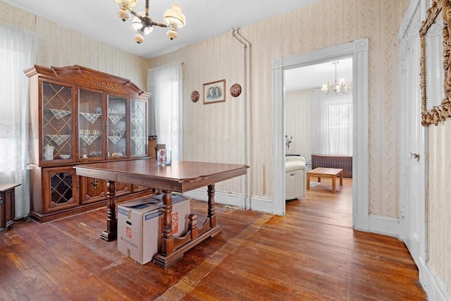 home office with wallpapered walls, wood-type flooring, baseboards, and an inviting chandelier