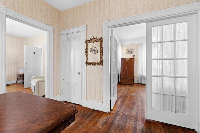 hall with wood finished floors, baseboards, and wallpapered walls