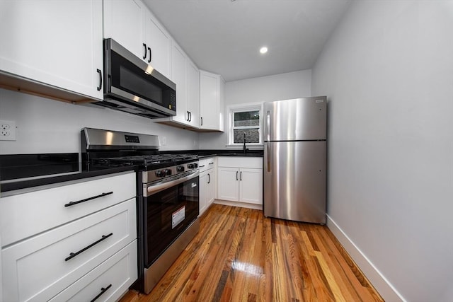 121 Horton St, Fall River, MA 02723 - kitchen featuring appliances with stainless steel finishes, dark countertops, white cabinetry, wood finished floors, and recessed lighting