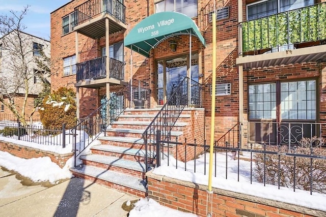 snow covered property entrance featuring brick siding